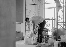 A construction worker pours materials inside a building under renovation.