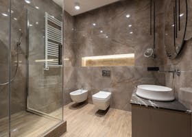 Elegant bathroom featuring marble walls, glass shower, and modern fixtures. Ideal for luxury home settings.